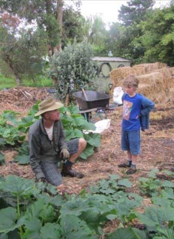 Neal instructing a boy dressed in blue on gardening.